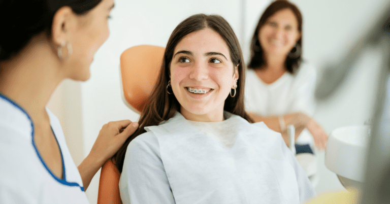 At Levine Orthodontics in Cape Coral, FL, a teenage girl with braces smiles at her orthodontist as an adult woman waits in the background.