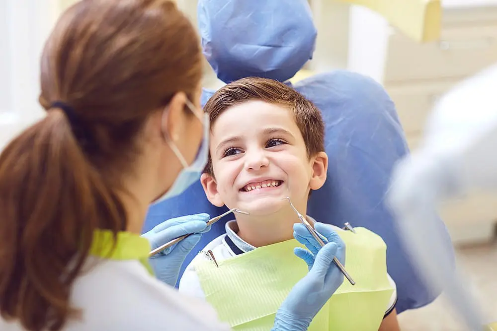 At Levine Orthodontics in Fort Myers, Cape Coral or Lehigh Acres FL, a child sits smiling in a dental chair as the professional explains tongue thrust during their check-up.