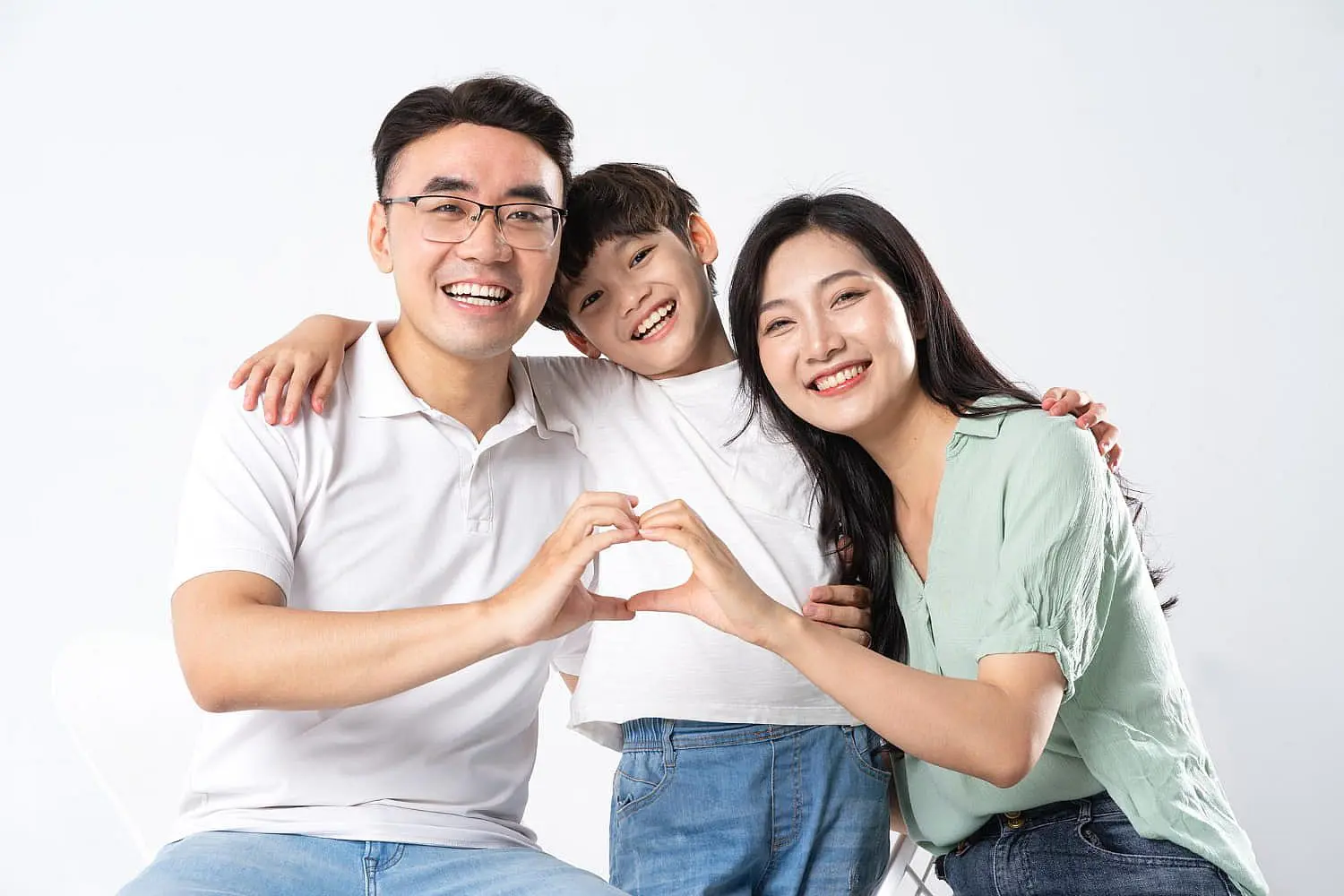 A man, woman, and young boy smile together as the adults form a heart with their hands, celebrating healthy family smiles—possibly thanks to Invisalign insurance coverage at Levine Orthodontics in Fort Myers, Cape Coral or Lehigh Acres, FL.