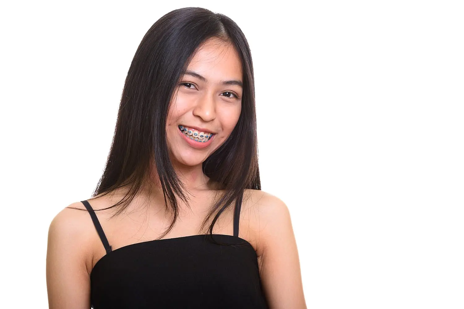 A young woman with long dark hair and metal braces, wearing a sleeveless black top, smiles at the camera against a white background—an example of the confident results achieved with Levine Orthodontics in Fort Myers, Cape Coral or Lehigh Acres, FL.