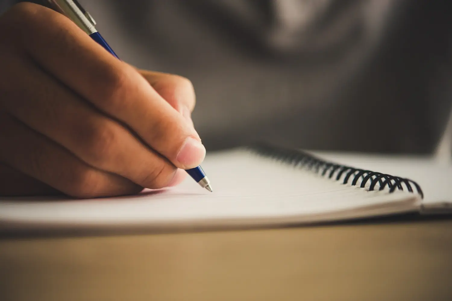 Someone takes notes about orthodontic insurance plans at Levine Orthodontics in Fort Myers, Cape Coral, or Lehigh Acres, FL, using a pen and a spiral-bound notebook.
