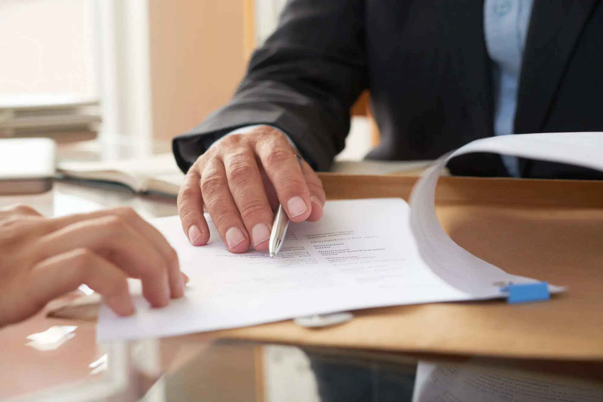 At Levine Orthodontics in Fort Myers, Cape Coral or Lehigh Acres, FL, two people sit at a desk reviewing documents, possibly discussing Invisalign insurance coverage as one prepares to sign a contract.