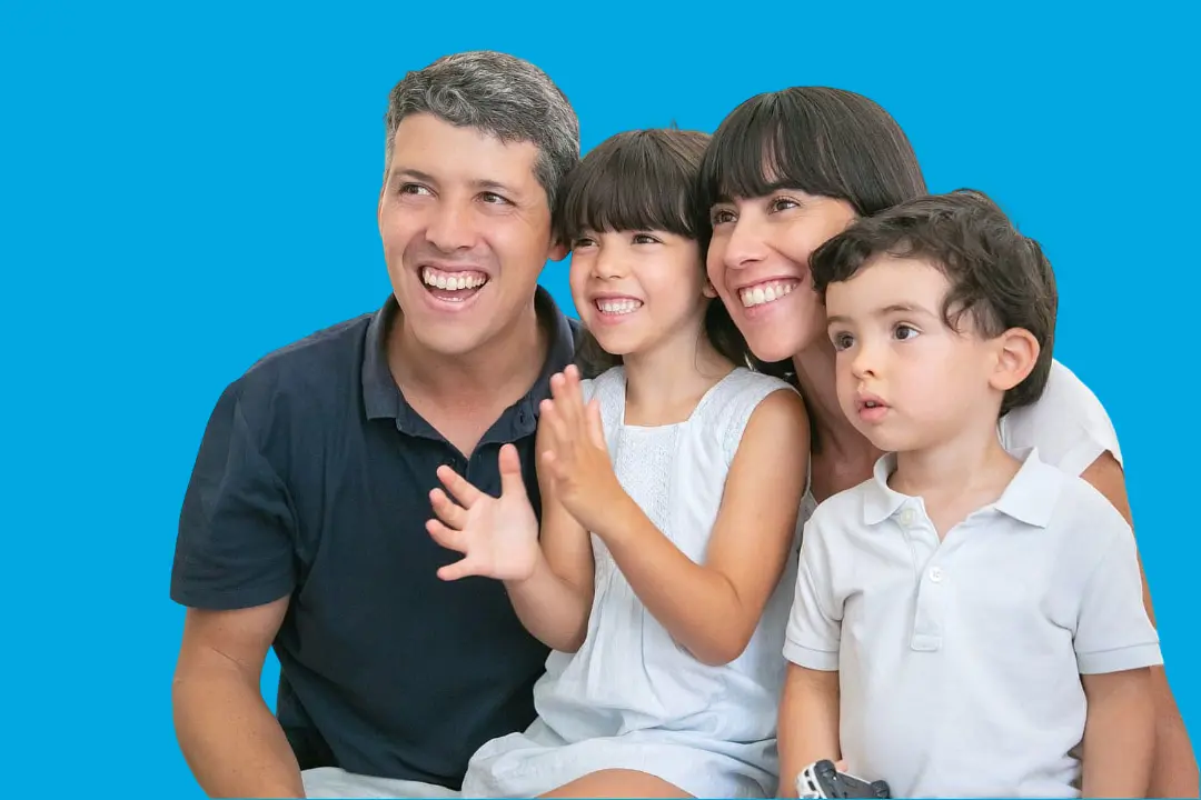 Smiling together against a solid blue background, a family of four—two adults and two young children—exudes confidence from learning about Invisalign vs Braces at Levine Orthodontics in Fort Myers, Cape Coral, or Lehigh Acres, FL.