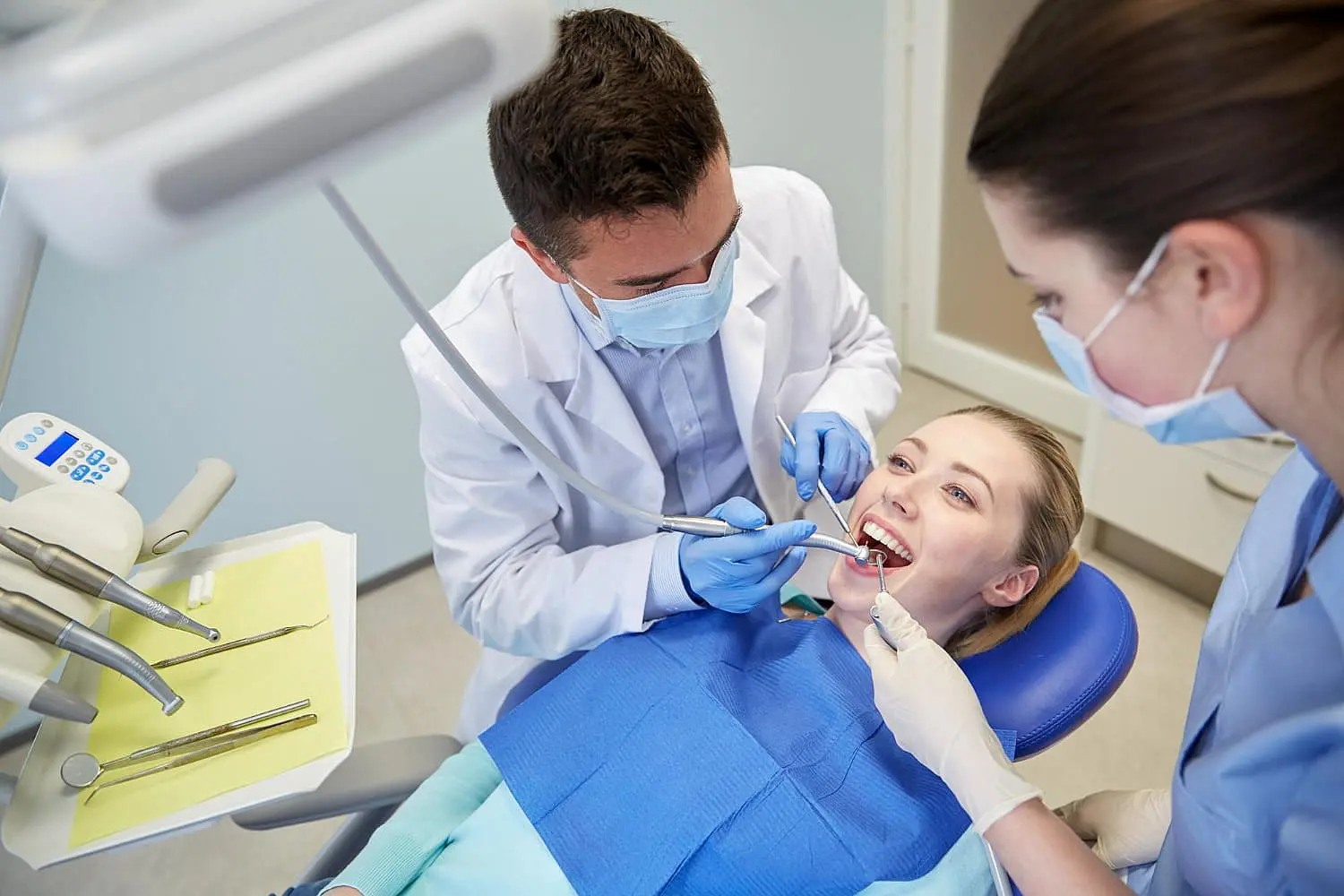 At Levine Orthodontics in Lehigh Acres FL, a dentist and dental assistant use specialized instruments to perform an Invisalign procedure on a patient in the dental chair.