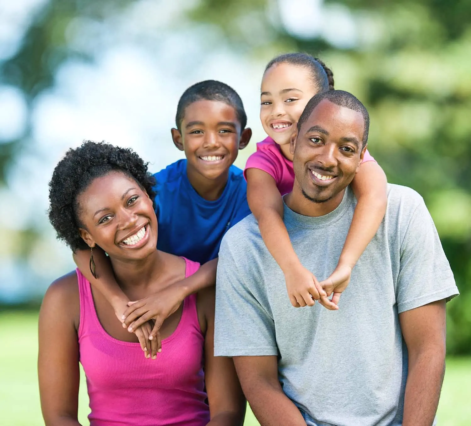 A family of four shows off their confident smiles achieved with Invisalign, posing outdoors for the camera—thanks to Levine Orthodontics in Cape Coral, FL.