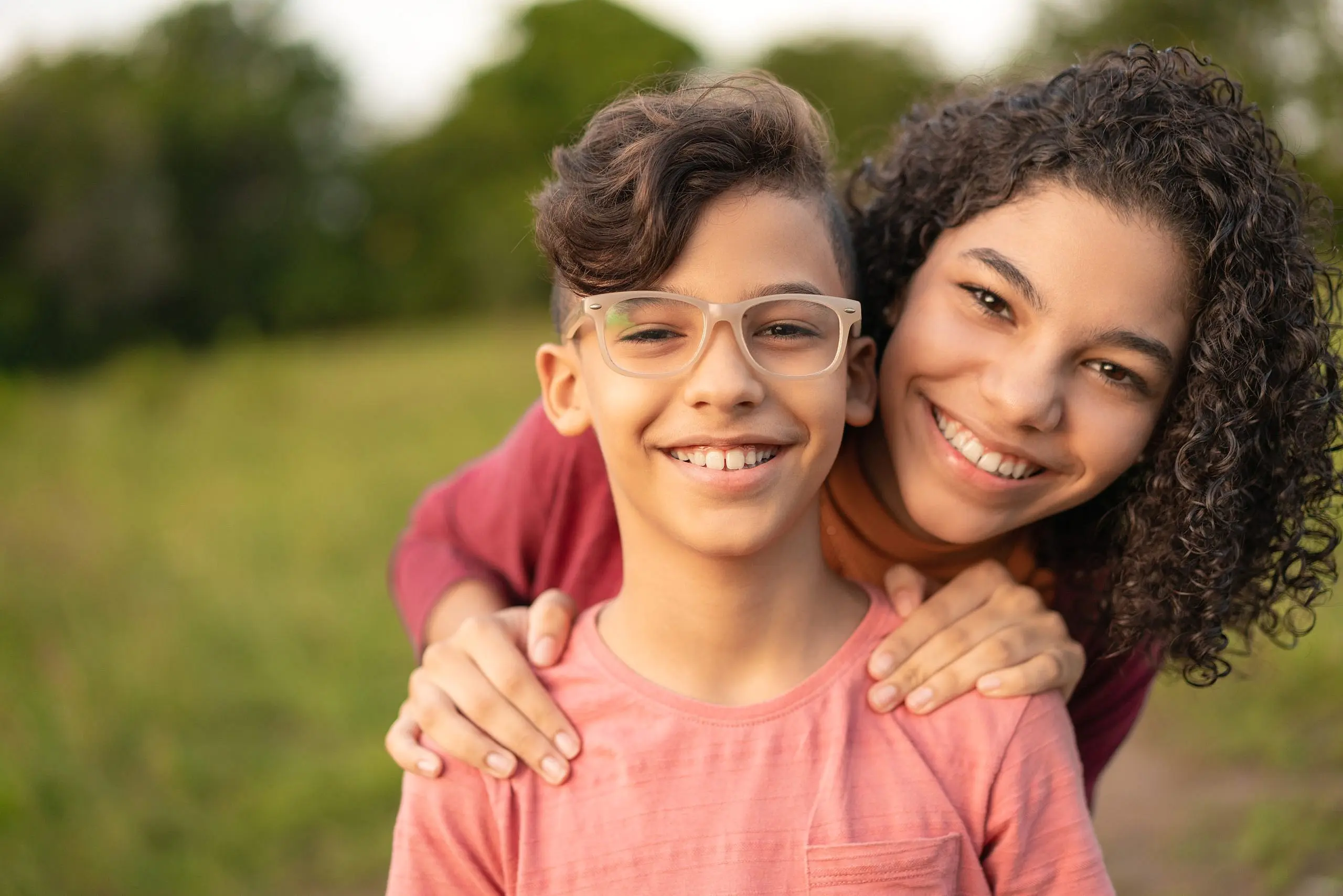 Smiling for the camera, a young boy in glasses and a pink shirt stands outside with an older girl behind him, her hands on his shoulders. Patients at Levine Orthodontics in Fort Myers, Cape Coral or Lehigh Acres, FL may be interested to know if Invisalign is covered by insurance.