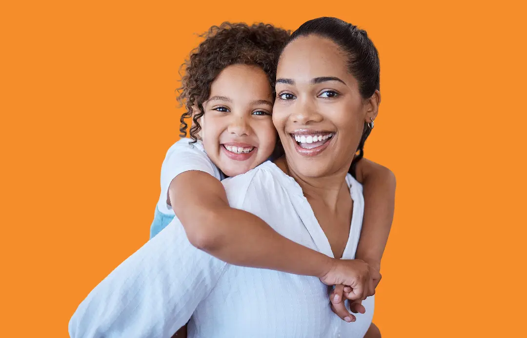 Showcasing confident smiles thanks to orthodontic appliances, a smiling woman carries a happy young girl on her back, both looking at the camera—representing Levine Orthodontics in Fort Myers, Cape Coral, or Lehigh Acres, FL.