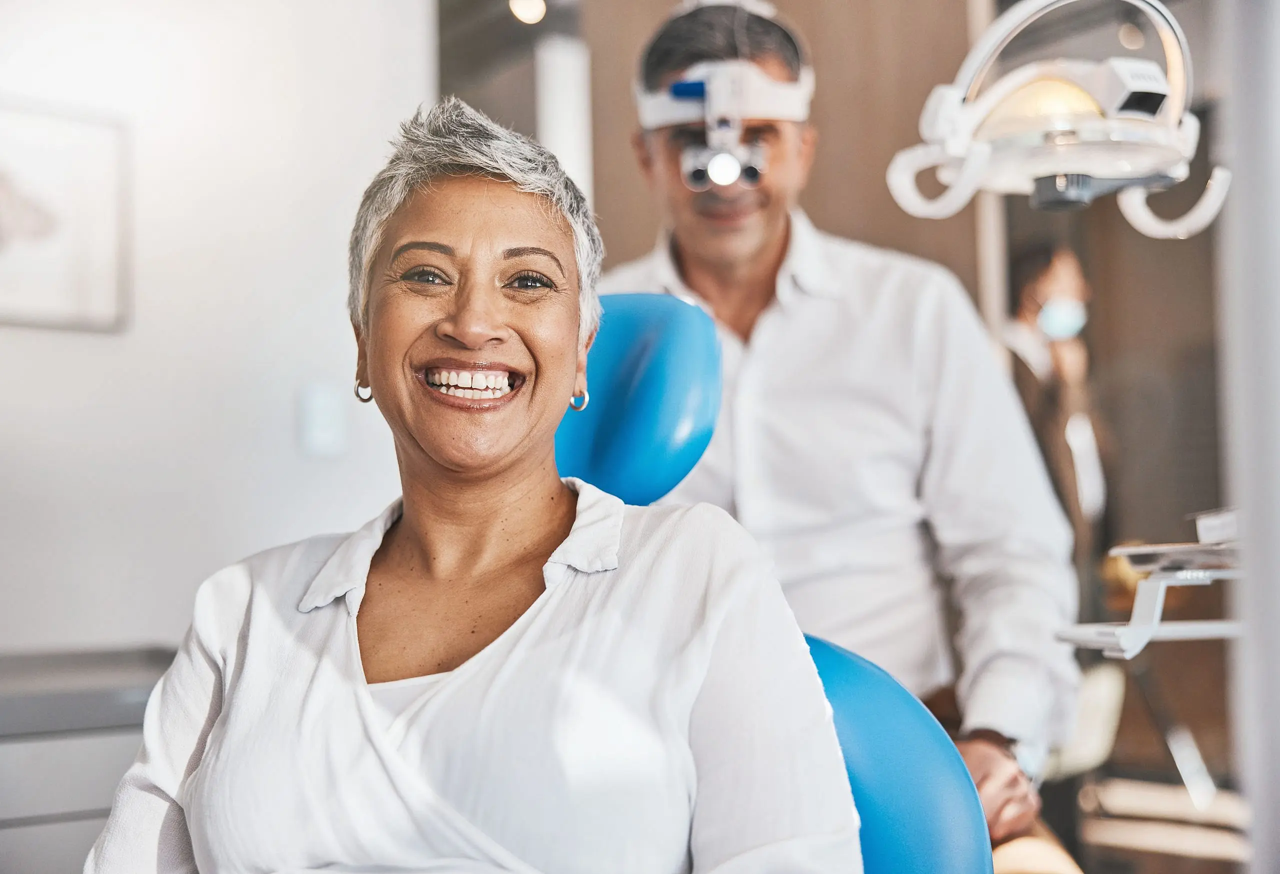 At Levine Orthodontics in Fort Myers, Cape Coral, or Lehigh Acres, FL, a smiling woman relaxes in a brightly lit dental chair as her dentist—wearing magnifying glasses—demonstrates the practice’s welcoming atmosphere and flexible braces payment plans.