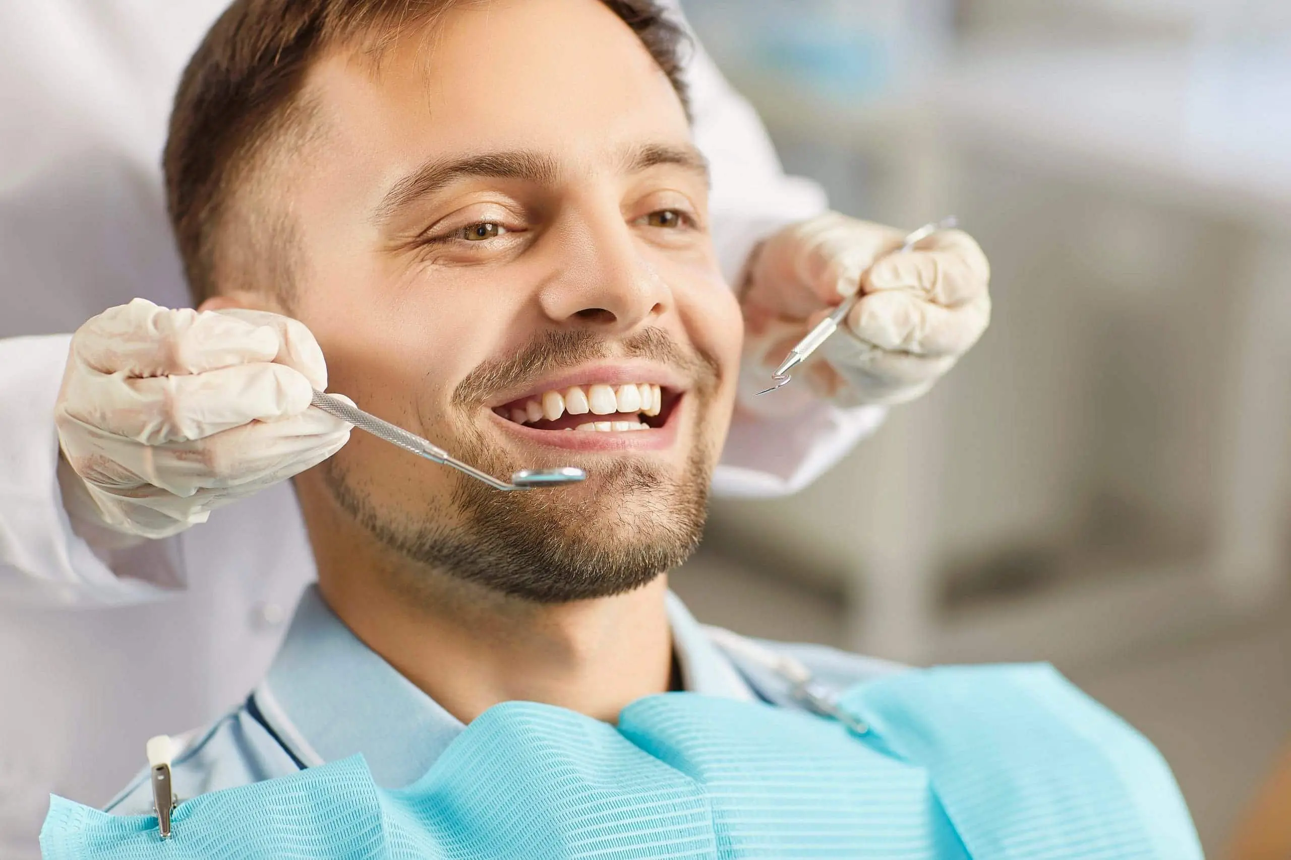 At Levine Orthodontics in Fort Myers, Cape Coral, or Lehigh Acres, FL, a smiling man possibly a mouth breather sits in a dental chair as a gloved dentist prepares with dental tools.