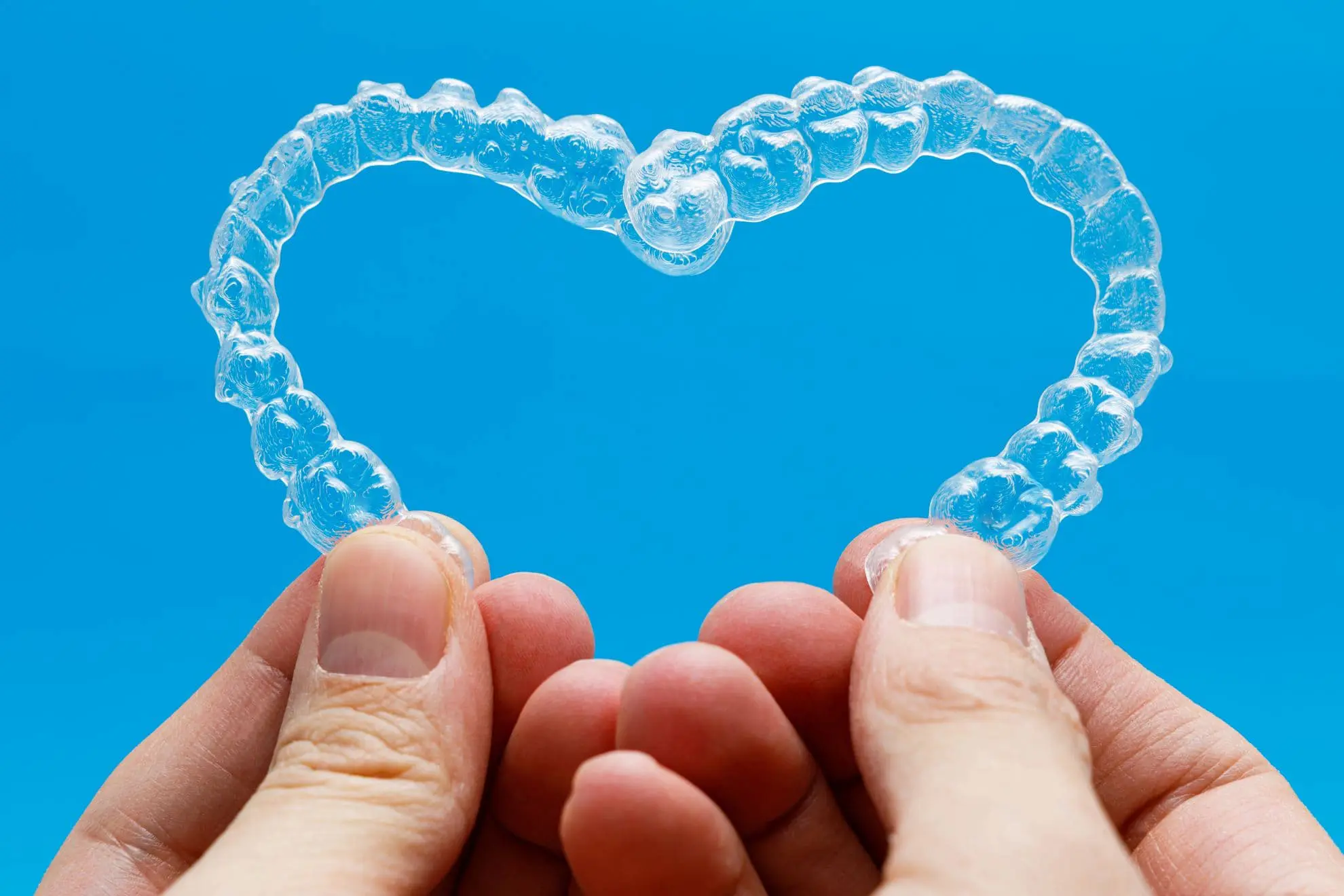Showcasing an Invisalign clear dental aligner against a blue background, Levine Orthodontics in Fort Myers, Cape Coral, or Lehigh Acres, FL highlights the promise of a confident smile with affordable Invisalign treatment options.