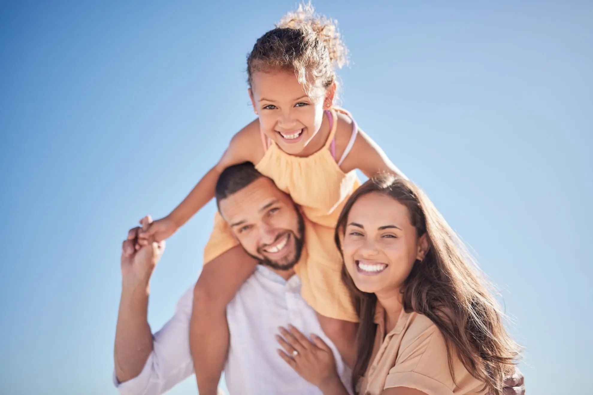 A smiling family—father carrying his daughter on his shoulders and mother standing beside them—symbolizes the supportive families exploring tongue thrust evaluations and treatment options at Levine Orthodontics in Fort Myers, Cape Coral, or Lehigh Acres, FL.