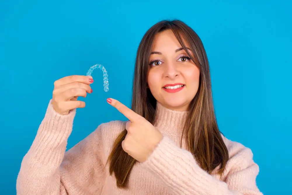 young beautiful woman holding invisalign clear aligners - Can Invisalign Fix Overbite in Fort Myers, Cape Coral, and Lehigh Acres, FL.