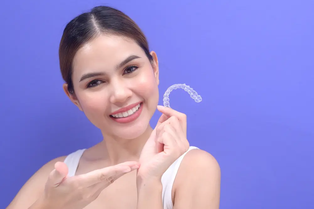 young smiling woman holding invisalign clear aligners - Can Invisalign Fix Overbite in Fort Myers, Cape Coral, and Lehigh Acres, FL. 
