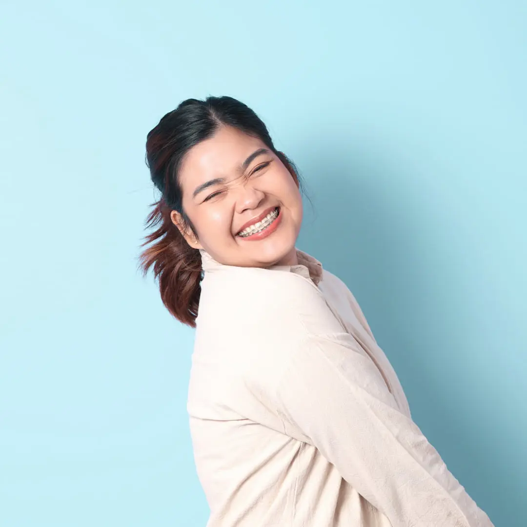 Woman smiling confidently against a blue background after orthodontic treatment at Levine Orthodontics in Fort Myers, Cape Coral, or Lehigh Acres, FL. Services include braces, Invisalign, clear aligners, and comprehensive orthodontic care for all ages.