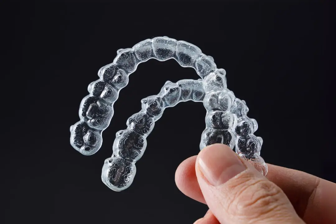 Person holding Invisalign clear aligners, showcasing discreet orthodontic treatment options from Levine Orthodontics in Cape Coral, FL.