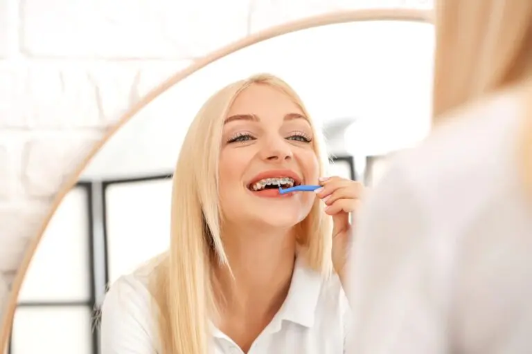 young woman metal braces toothbrush home - How to Floss with Braces in Fort Myers, Cape Coral, and Lehigh Acres, FL.