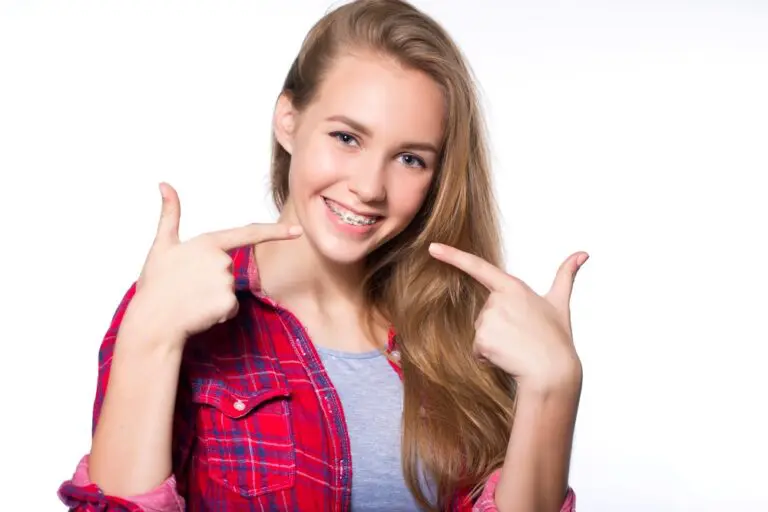 beautiful young blondie girl showing her metal braces isolated white - How to Get Braces Glue Off Teeth in Fort Myers, Cape Coral, and Lehigh Acres, FL