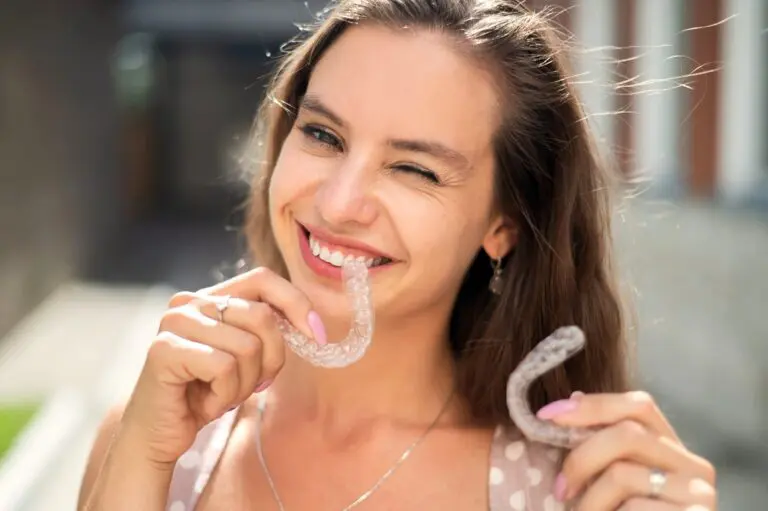 beautiful caucasian woman holding invisalign clear aligners for bite correction - Aligner vs Braces in Fort Myers, Cape Coral, and Lehigh Acres, FL