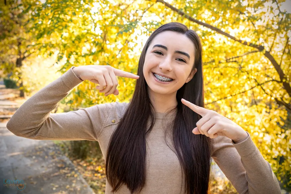 beautiful smiling girl showing metal braces teeth orthodontics dental theme - Aligner vs Braces in Fort Myers, Cape Coral, and Lehigh Acres, FL