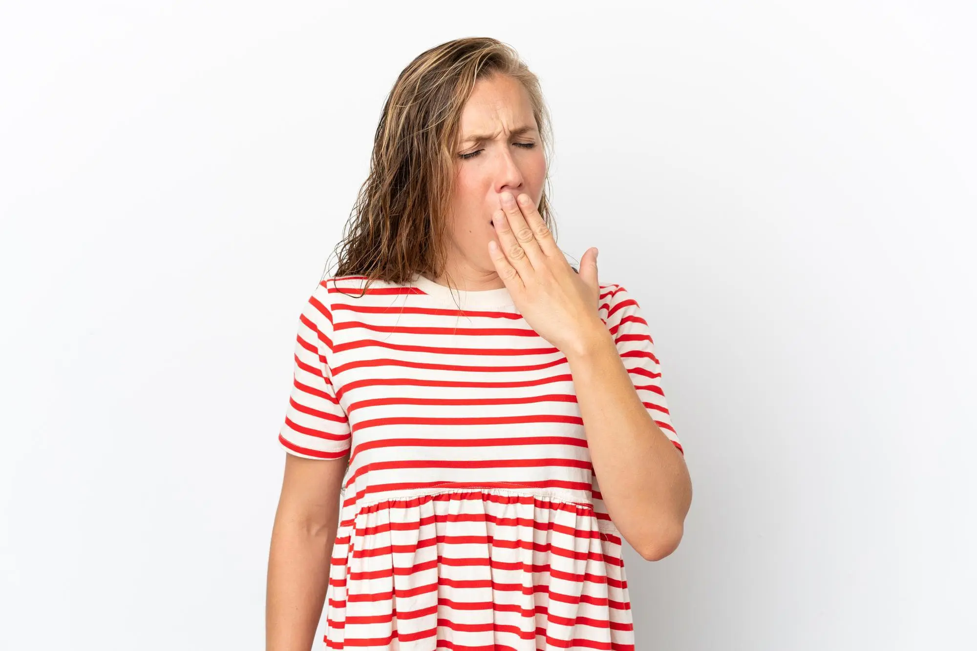 A woman yawns in a red and white striped shirt, symbolizing restful breathing from Levine Orthodontics in Lehigh Acres, FL.